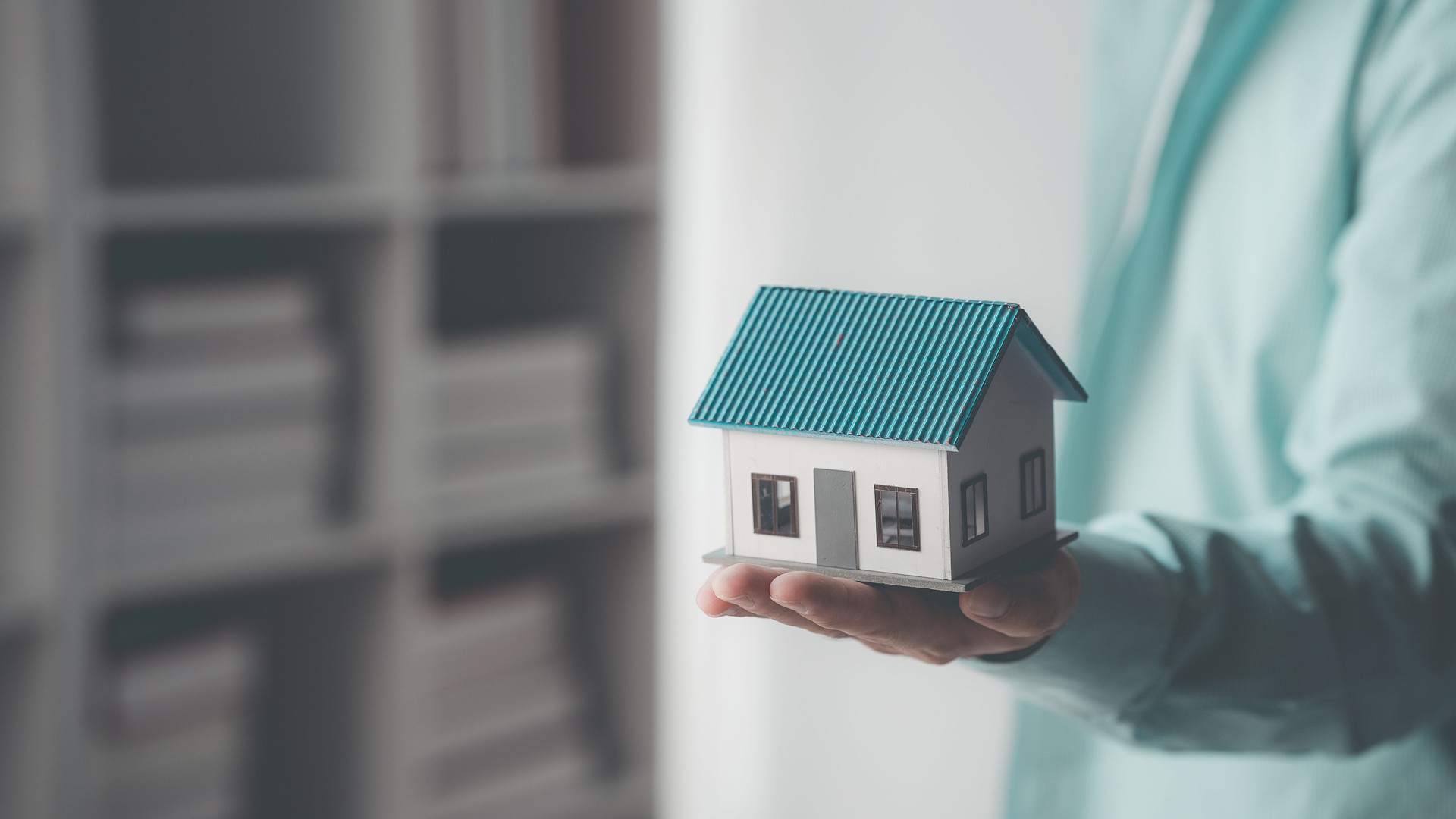 Home loan concept close up of hand holding real estate house model in hand of home insurance broker real estate concept